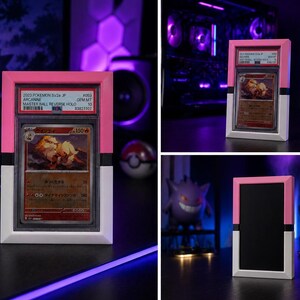 May include: A framed Pok&eacute;mon trading card with a pink and white border. The card features a fiery creature illustration and Japanese text. The frame has a black stripe and the text "2023 Pokemon SV2a Jp" is visible.