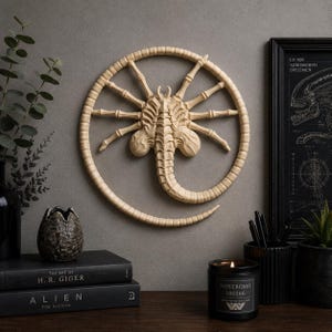 May include: A beige, circular wall sculpture depicting a facehugger with a segmented tail and multiple spindly legs. The creature is centred within a thin, circular frame, showcasing intricate, organic textures and a pale, bone-like finish.