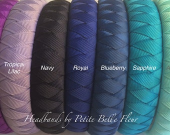 May include: A collection of eight padded headbands featuring a braided ribbon texture in various colors labeled Deep Purple, Purple, Tropical Lilac, Navy, Royal, Blueberry, Sapphire, Aquamarine, and Light Blue, with the text Headbands by Petite Belle Fleur.