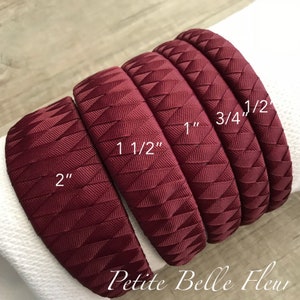 May include: A collection of burgundy headbands with a textured, geometric design. The headbands vary in width, labeled as 2", 1 1/2", 1", 3/4", and 1/2". The brand name "Petite Belle Fleur" is printed at the bottom.
