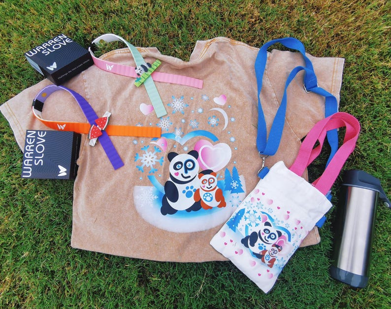 Puede incluir: Una colecci&oacute;n de art&iacute;culos con tem&aacute;tica de panda, que incluye una camiseta color canela con un gr&aacute;fico de panda, una bolsa tote blanca, un cord&oacute;n azul y una botella de agua de acero inoxidable. Tambi&eacute;n se incluyen varias pulseras coloridas y dos cajas negras con el texto "WARREN SLOVE".