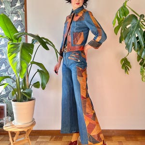 May include: A denim jacket and matching wide-leg trousers set featuring brown, orange, and tan leather patchwork panels. The jacket has a collar, front buttons, and chest pockets. The trousers feature a high waist and flared legs with leather accents.