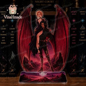 May include: A clear acrylic standee featuring a male figure with large red wings holding a female figure in a black dress. The background depicts a dark, mountainous landscape under a red sky. The base is rectangular and matches the landscape art.