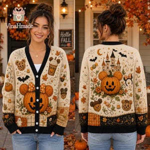 May include: A beige button-up cardigan featuring a Halloween-themed pattern with jack-o'-lanterns, Mickey Mouse-shaped pumpkins, ghosts, bats, a castle, and autumn leaves. The garment has a black trim along the button placket and cuffs.