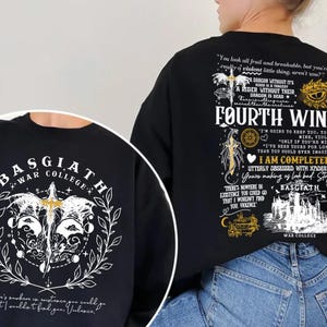 May include: Black sweatshirt featuring the text "FOURTH WING" and "BASGIATH WAR COLLEGE". The design includes a dragon, sword, and other graphic elements in white and gold. The back of the sweatshirt has additional text and illustrations.