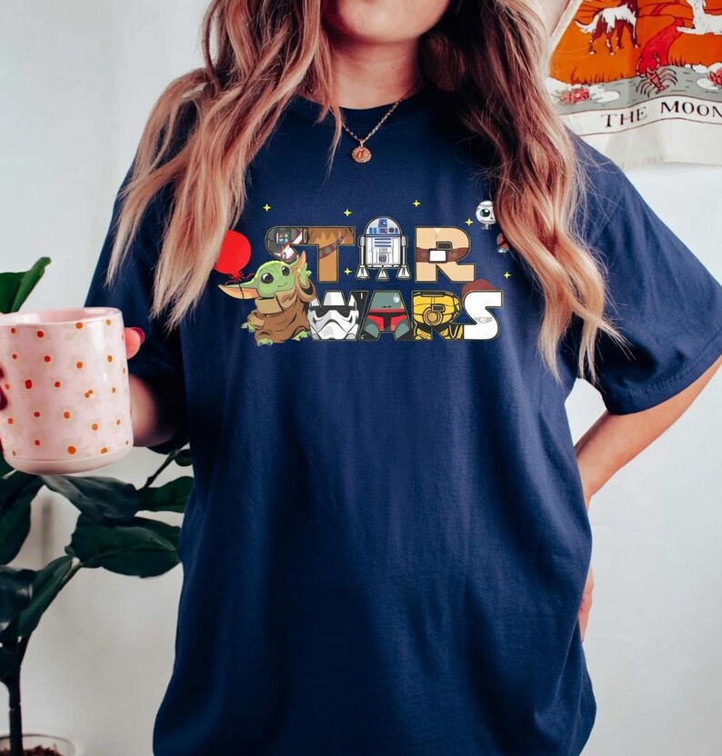 May include: A white ceramic mug with a black handle and the text "But First, Coffee" in a bold, black font. The mug is set against a blurred background, suggesting a cosy setting.