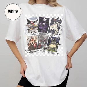 May include: White t-shirt featuring a graphic of characters from The Nightmare Before Christmas. The design includes images of Sally, Jack Skellington, Zero, the Mayor, Lock, Shock, Barrel, and Oogie Boogie. Bats and stars are also included.