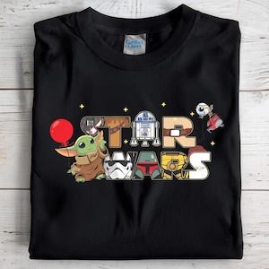 May include: Black t-shirt with a colourful cartoon design of "STAR WARS" and characters like Baby Yoda and R2-D2. The design includes a red balloon held by Baby Yoda and other iconic Star Wars figures.