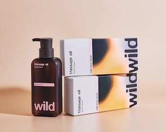 May include: A dark brown plastic pump bottle of Wild Massage oil Atomic Rose next to two stacked rectangular white and orange boxes. The packaging features the text Massage oil, Atomic Rose, Wild Rose Reset, and the brand name wild in bold.