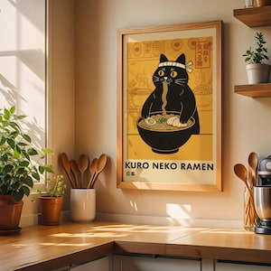 Könnte beinhalten: Ein gerahmter Kunstdruck mit einer schwarzen Katze, die ein Stirnband trägt und Ramen aus einer großen Schüssel isst. Die Illustration ist auf gelbem Hintergrund mit japanischem Text und dem Schriftzug KURO NEKO RAMEN unten.