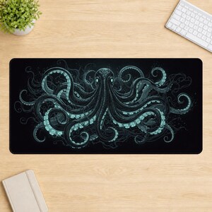 Peut inclure: Un tapis de bureau rectangulaire présentant une grande illustration détaillée d'une pieuvre centrée sur un fond noir. La pieuvre est représentée dans des tons bleu foncé et sarcelle, avec des yeux bleu clair lumineux et des ventouses.