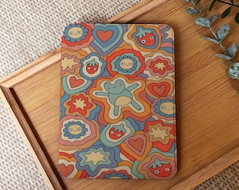 May include: A rectangular, colorful phone case featuring a retro design with a light blue frog, hearts, flowers, and strawberries. The case has a groovy, psychedelic aesthetic with a mix of orange, red, blue, and yellow hues.