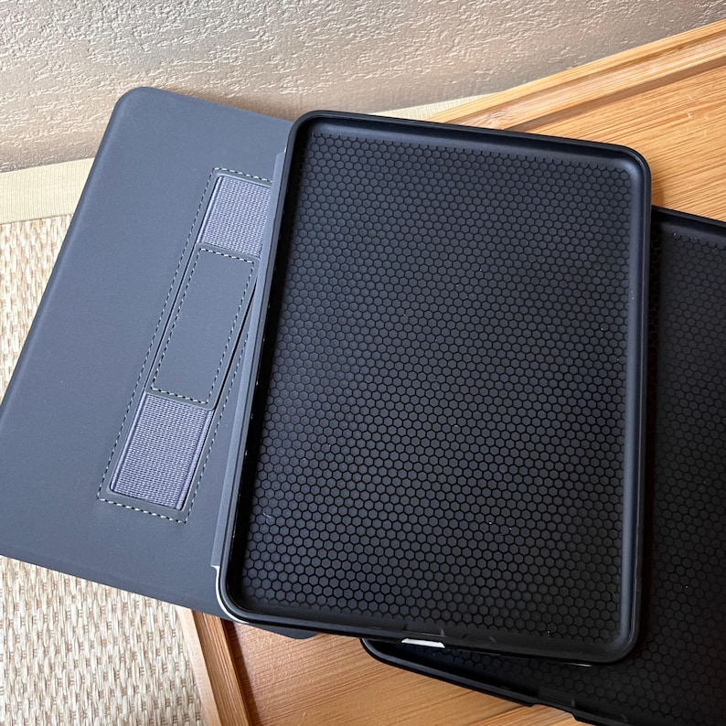 Puede incluir: Una funda gris para tableta con un soporte incorporado y una funda interior negra. La funda interior tiene un patr&oacute;n de panal texturizado. El soporte est&aacute; hecho de material el&aacute;stico gris y est&aacute; cosido a la funda.