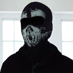 May include: Black balaclava with a white skull design on the front. The balaclava covers the head and neck, with openings for the eyes and mouth. The skull design has a distressed, textured appearance.