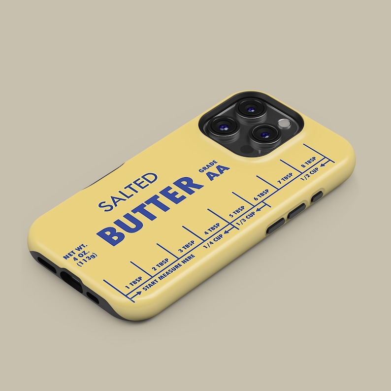 May include: A yellow phone case with a stick of butter design. The case has a black border and a blue label that reads "SALTED BUTTER GRADE AA". The label also includes a measurement guide in tablespoons and cups.
