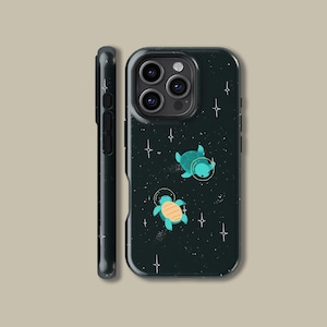 May include: A dark green phone case with a design of two cartoon turtles in space suits against a starry background. The turtles are teal and orange, with gold-coloured helmets. The case is shown from the front and side.