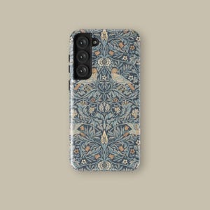 May include: A phone case with a navy blue floral pattern featuring birds, leaves, and flowers in shades of blue, beige, and orange. The case has a glossy finish and a camera module with three lenses.