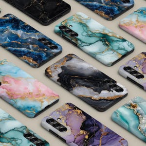 May include: A selection of smartphone cases with marble patterns. The cases display a range of colours, such as black, blue, pink, purple, and teal, with gold veining. The cases are arranged in a grid formation.