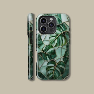 May include: A smartphone case featuring a green and gold monstera leaf design. The case has a mosaic-like pattern with dark green leaves and gold outlines. The case is shown from the front and side, showcasing the design and the phone's camera.