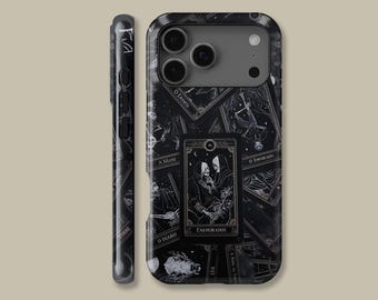 May include: Black phone case featuring a tarot card design with the words "ENAMORADOS" and other text. The case has a dark, gothic aesthetic with illustrations of skeletons and other imagery. The case is shown from the front and side.