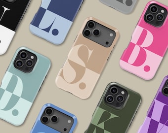 May include: A selection of phone cases in different colours, each displaying a large initial letter. The cases are in black, blue, pink, green, and beige, with a two-tone colour block design. The letters are in a bold, sans-serif font.
