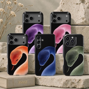 May include: Five black smartphone cases featuring a graphic of a snake head with a protruding tongue. Each case displays a different coloured snake: purple, pink, orange, blue, and green. The cases have a camera cutout and a smooth, glossy finish.