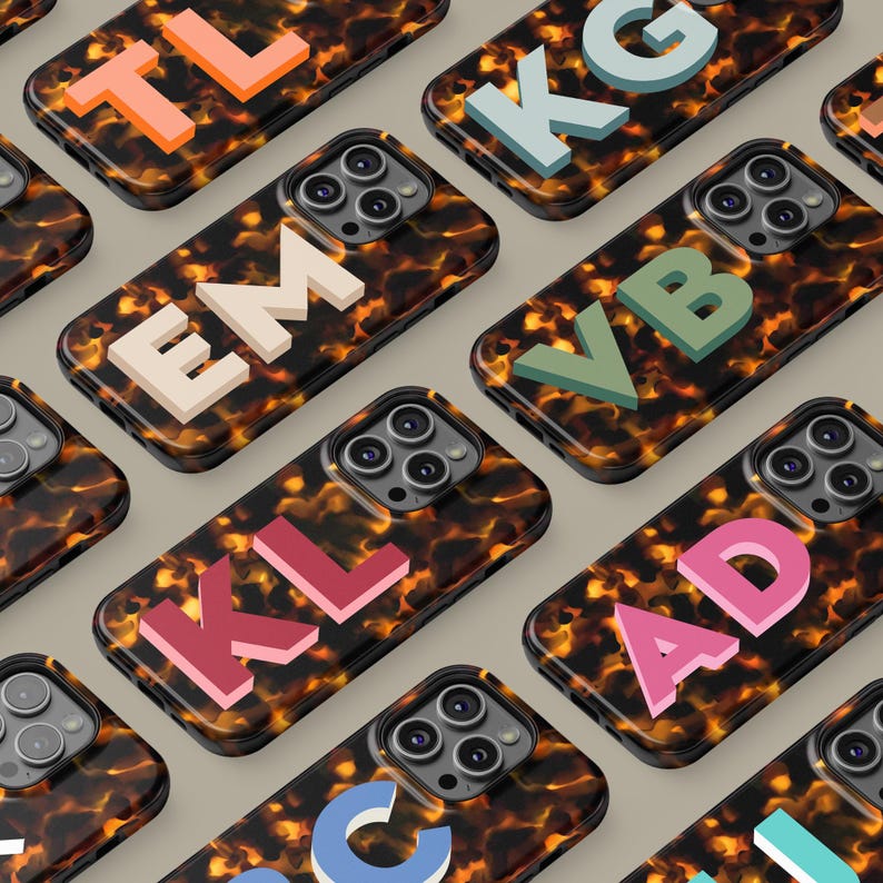 Puede incluir: Una colecci&oacute;n de fundas para tel&eacute;fono con diferentes letras. Las fundas est&aacute;n hechas de un material con estampado de caparaz&oacute;n de tortuga y presentan una variedad de colores. Las letras son en 3D y est&aacute;n en relieve en la superficie de la funda.