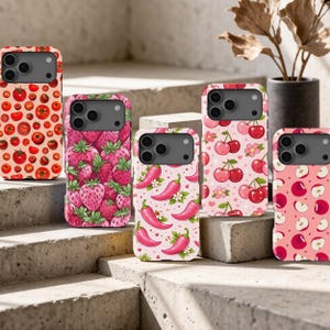 May include: Five smartphone cases featuring colorful fruit and vegetable patterns. The designs include red tomatoes, pink strawberries, pink chili peppers, red cherries with small flowers, and red apple slices on various shades of pink backgrounds.