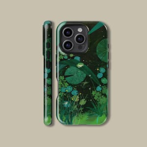 Puede incluir: Funda de teléfono verde que presenta una escena de estanque con nenúfares, una rana y plantas acuáticas. La funda tiene un acabado brillante y una combinación de colores verde oscuro. El lateral de la funda también es verde y tiene un acabado liso.