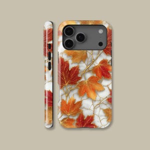 May include: A phone case featuring a design of autumn leaves in shades of red, orange, and gold. The leaves are set against a white marble background with gold-colored veins. The case has a glossy finish and a camera cutout.