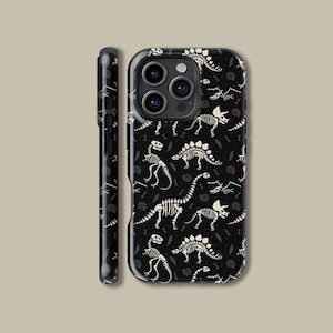 May include: Black phone case featuring a repeating pattern of white dinosaur skeletons and fossils. The case has a glossy finish and a protective design, with a side view showing the case's thickness and button details. The design includes various dinosaur species.