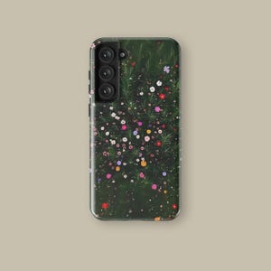 May include: A phone case featuring a vibrant floral design. The case has a dark green background with a pattern of colorful flowers in shades of red, pink, yellow, and white. The phone case has a camera module with three lenses.