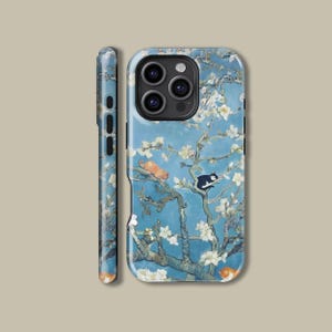 May include: A blue and white phone case featuring a painting of a blossoming tree and cats. The case has a cut-out for the camera lens.