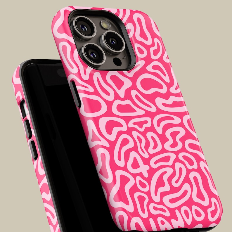 May include: A hot pink phone case with a white abstract pattern. The case is shown on a black phone, with the camera lenses visible. The design features a repeating, organic shape.