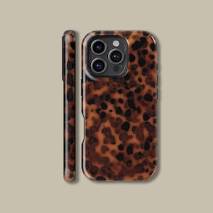 Puede incluir: Una funda de teléfono con un diseño de carey. La funda es marrón con manchas negras y tiene un acabado brillante. La imagen muestra la parte delantera y lateral de la funda.