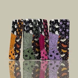 May include: Four Halloween-themed phone cases with patchwork designs. Each case features a different color scheme, including orange, green, pink, and purple. The designs include ghosts, bats, spiderwebs, stars, and pumpkins, creating a festive look.