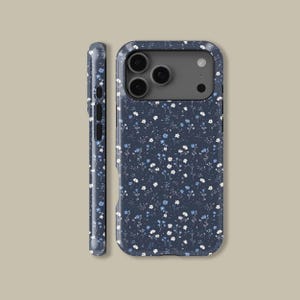 May include: A navy blue phone case with a delicate floral pattern. The case features a repeating design of small white and light blue flowers and green stems. The case is shown from the front and side.