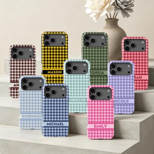 May include: A collection of phone cases featuring a gingham check pattern in various colors including yellow, green, red, brown, light blue, dark blue, mint, purple, and pink. Each case has a horizontal band with a printed name like Mason or Emily.