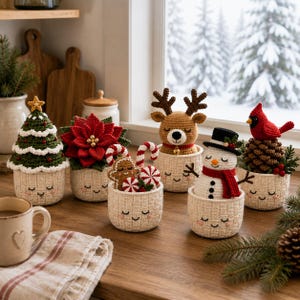 May include: A collection of six crocheted holiday figures in cream-colored woven baskets with embroidered faces. The set includes a Christmas tree, a red poinsettia, a gingerbread person with candy canes, a reindeer, a snowman, and a cardinal.