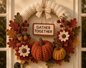 May include: A crochet wreath featuring a cream-colored base, a central sign with the text GATHER TOGETHER, two pumpkins in orange and yellow, and various autumn-themed elements including oak leaves, flowers, and berries in shades of red and brown.