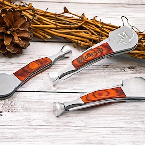 May include: Three silver and wood handled tools with the word "Morgan" engraved on the wood. The tools have a silver metal finish and a reddish-brown wood grain handle. One tool has the letter "M" and a deer antler design.