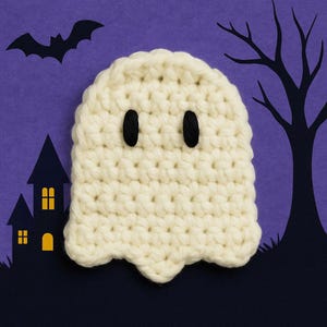 Op de afbeelding: Een handgemaakt, off-white gehaakt spook met zwarte knoopogen, tegen een paarse achtergrond met Halloween-silhouetten. Het spook heeft een afgeronde bovenkant en een geschulpte basis, ideaal voor seizoensdecoraties.