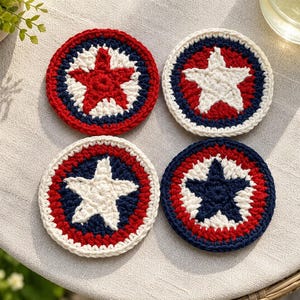 May include: Four handmade crochet coasters. Each coaster features a star design in the center, surrounded by concentric circles of red, white, and blue. The coasters are round and appear to be made of yarn.
