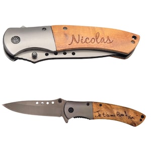 Peut inclure: Deux couteaux pliants avec des manches en bois et des lames argentées. L'un porte le nom "Nicolas" gravé sur le manche. L'autre porte l'inscription "Je t'aime Papa! Max" sur le manche.