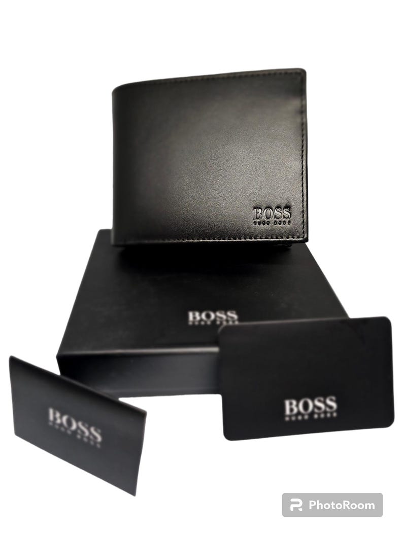 Pode incluir: Carteira de couro preta com o nome da marca "BOSS" em relevo. Apresentada numa caixa preta e acompanhada por dois cart&otilde;es pretos, tamb&eacute;m com o log&oacute;tipo "BOSS". A apresenta&ccedil;&atilde;o geral &eacute; elegante e minimalista.