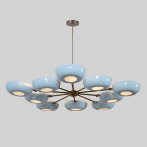 May include: A contemporary chandelier featuring ten light blue, bowl-shaped shades with a speckled pattern, suspended from a bronze-finished frame. The shades emit a warm light. The fixture hangs from a single rod.