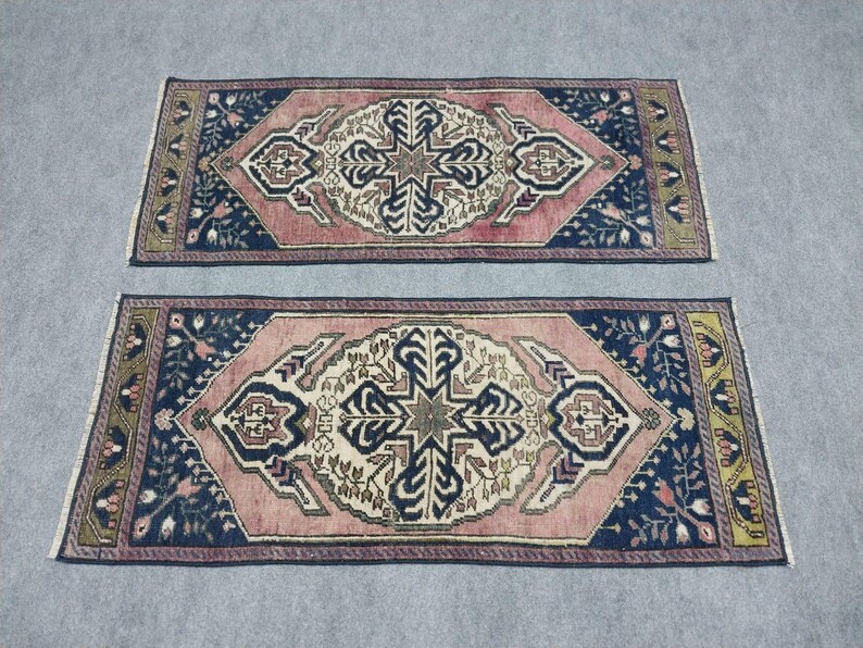 May include: Two rectangular rugs with a central medallion design. The rugs feature a pink field, navy blue borders, and intricate patterns in cream, brown, and green. The rugs have a traditional, oriental style.