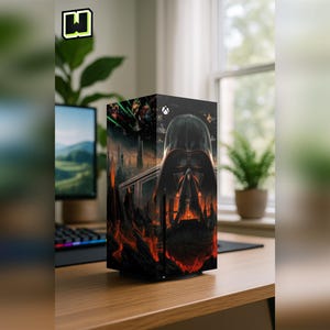 May include: A black and red Xbox Series X console skin featuring Darth Vader's helmet and a dark, fiery landscape. The console is on a wooden desk with a computer monitor and keyboard in the background. The Xbox logo is visible.