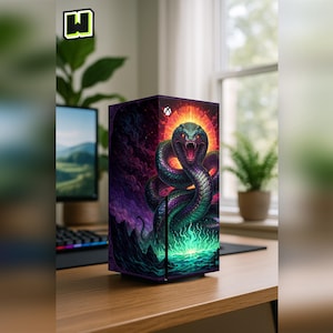 Peut inclure: Une console de jeu noire ornée d'une illustration vibrante d'un serpent avec un halo de feu. L'œuvre d'art présente un design coloré et détaillé avec des nuances de violet, de vert et de rouge. La console est posée sur un bureau en bois.