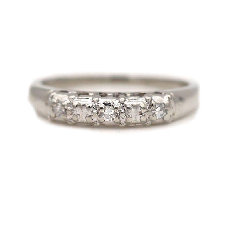 May include: A silver band with five small diamonds set in a row.